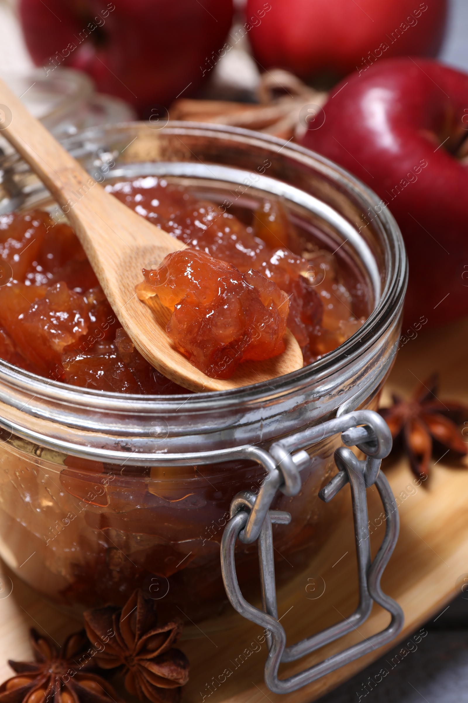 Photo of Delicious apple jam and spoon in jar on table, closeup