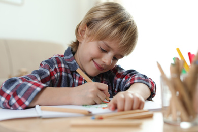 Photo of Little boy drawing at table indoors. Creative hobby