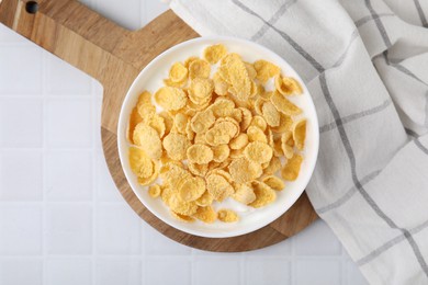 Photo of Breakfast cereal. Tasty corn flakes with milk in bowl on white tiled table, top view