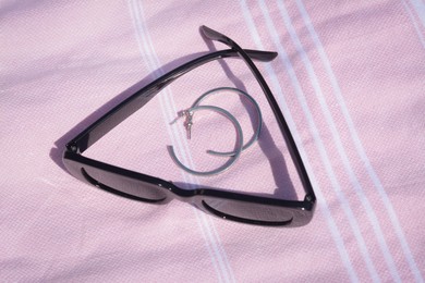 Photo of Stylish sunglasses and jewelry on pink blanket, above view