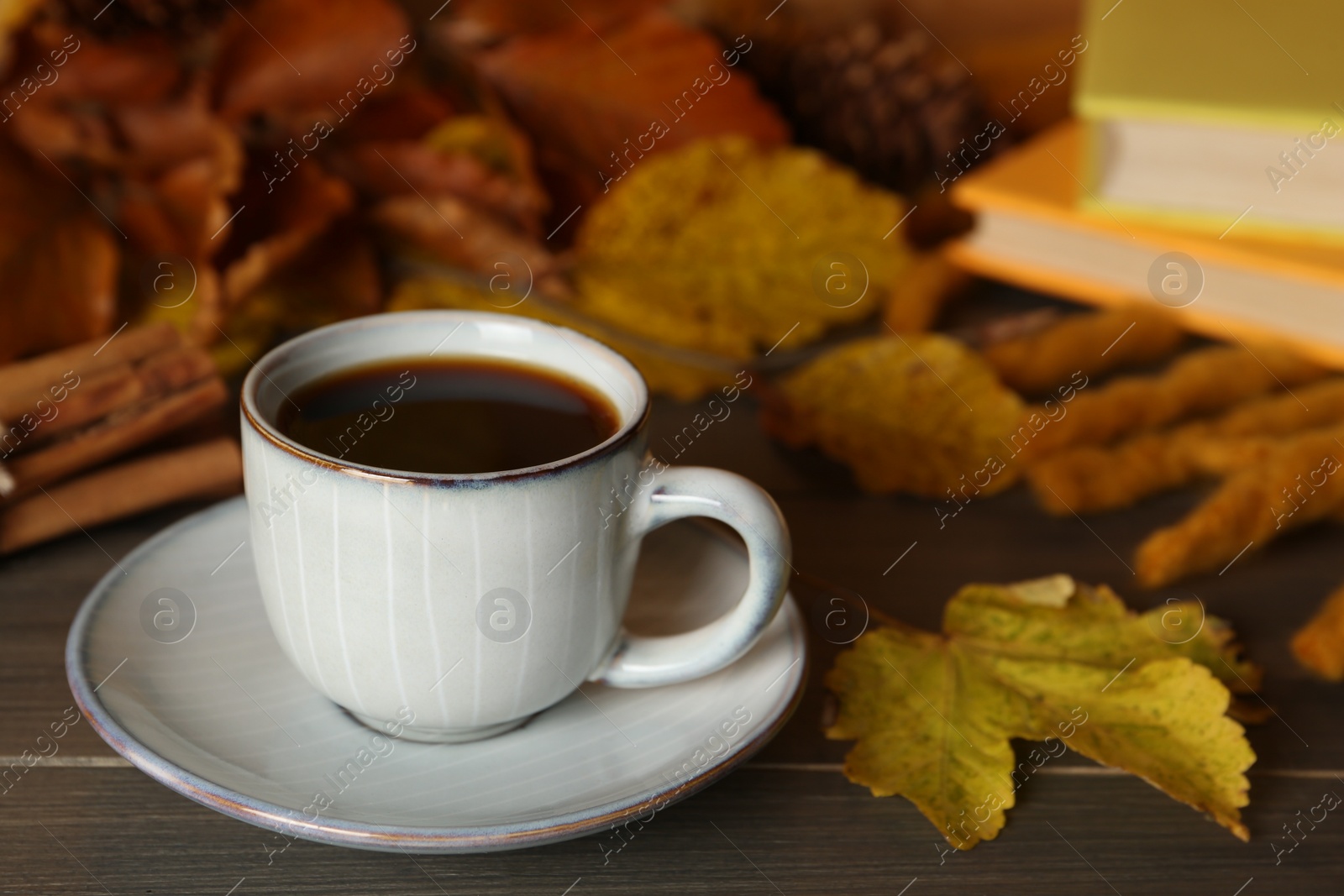 Photo of Composition with cup of hot coffee and autumn leaves on wooden table. Space for text