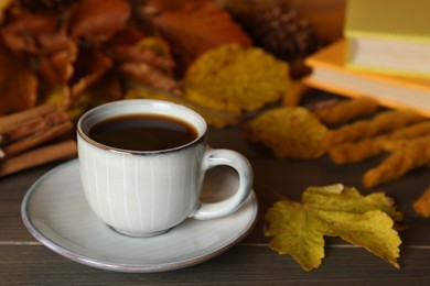 Photo of Composition with cup of hot coffee and autumn leaves on wooden table. Space for text