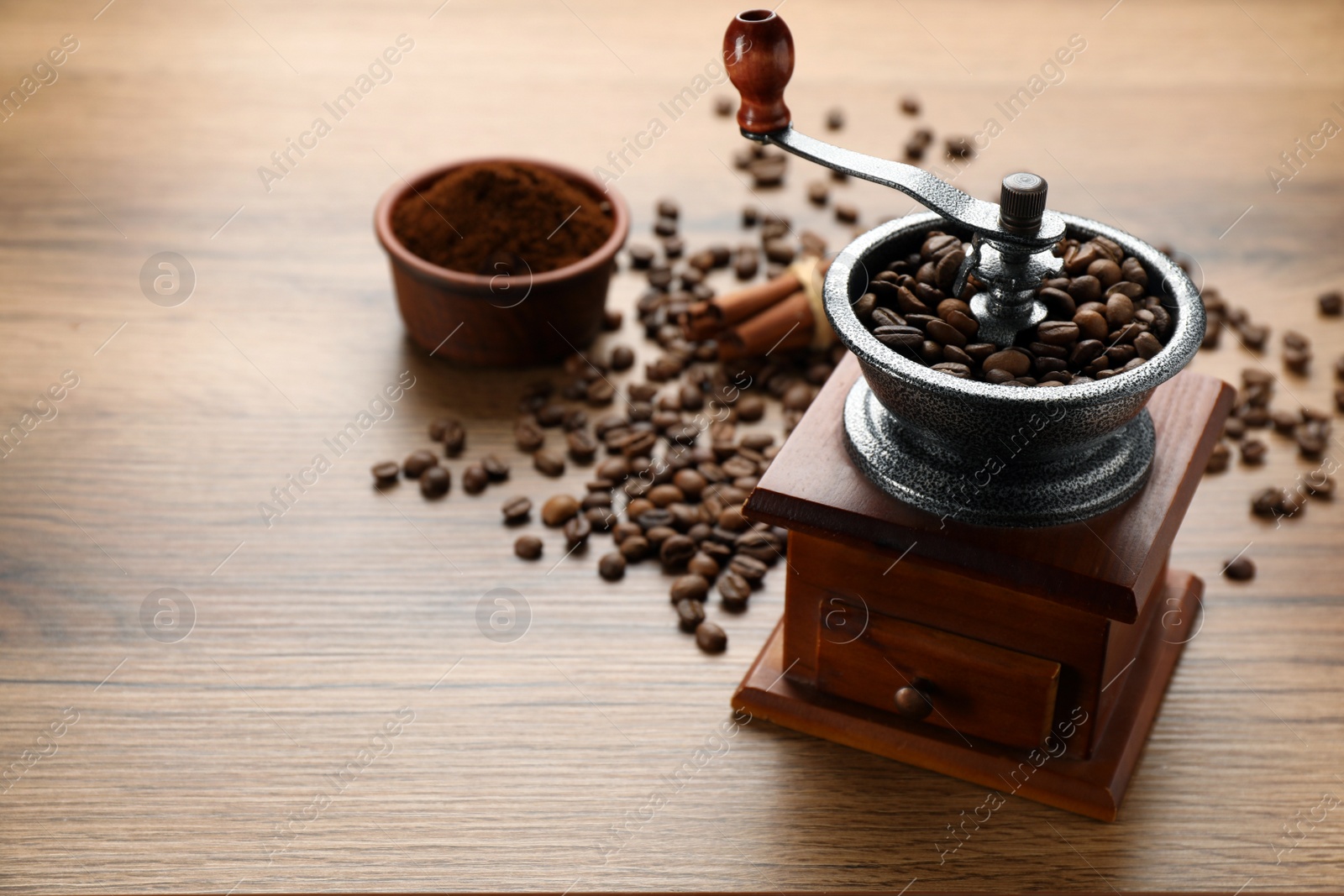 Photo of Vintage manual coffee grinder with beans and powder on wooden table. Space for text