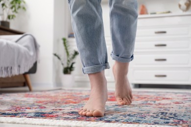 Photo of Woman standing on carpet with pattern in room, closeup