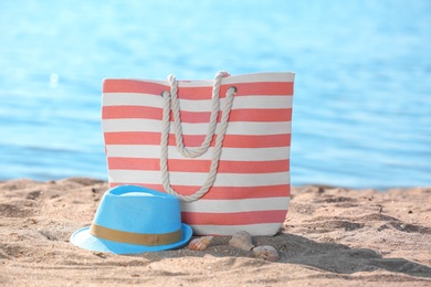 Photo of Bag and hat on sand near sea. Beach object