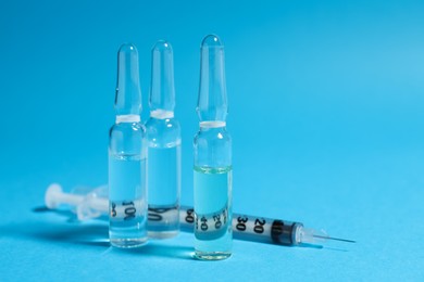 Photo of Pharmaceutical ampoules and syringe on light blue background