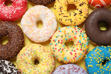 Photo of Delicious glazed donuts on yellow background, flat lay