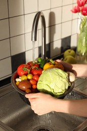 Photo of Woman washing different vegetables in metal colander, closeup