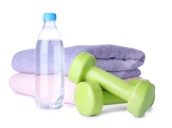 Photo of Stylish dumbbells, bottle of water and towels on white background. Home fitness