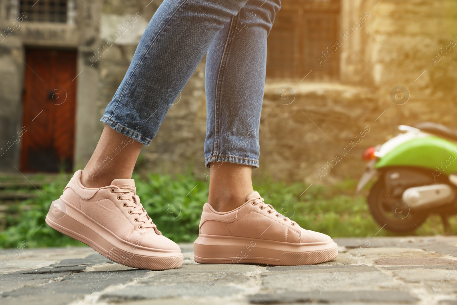 Photo of Woman in stylish sneakers walking on city street, closeup