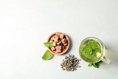 Photo of Cup with hot aromatic mint tea, dry leaves and sugar cubes on table, top view