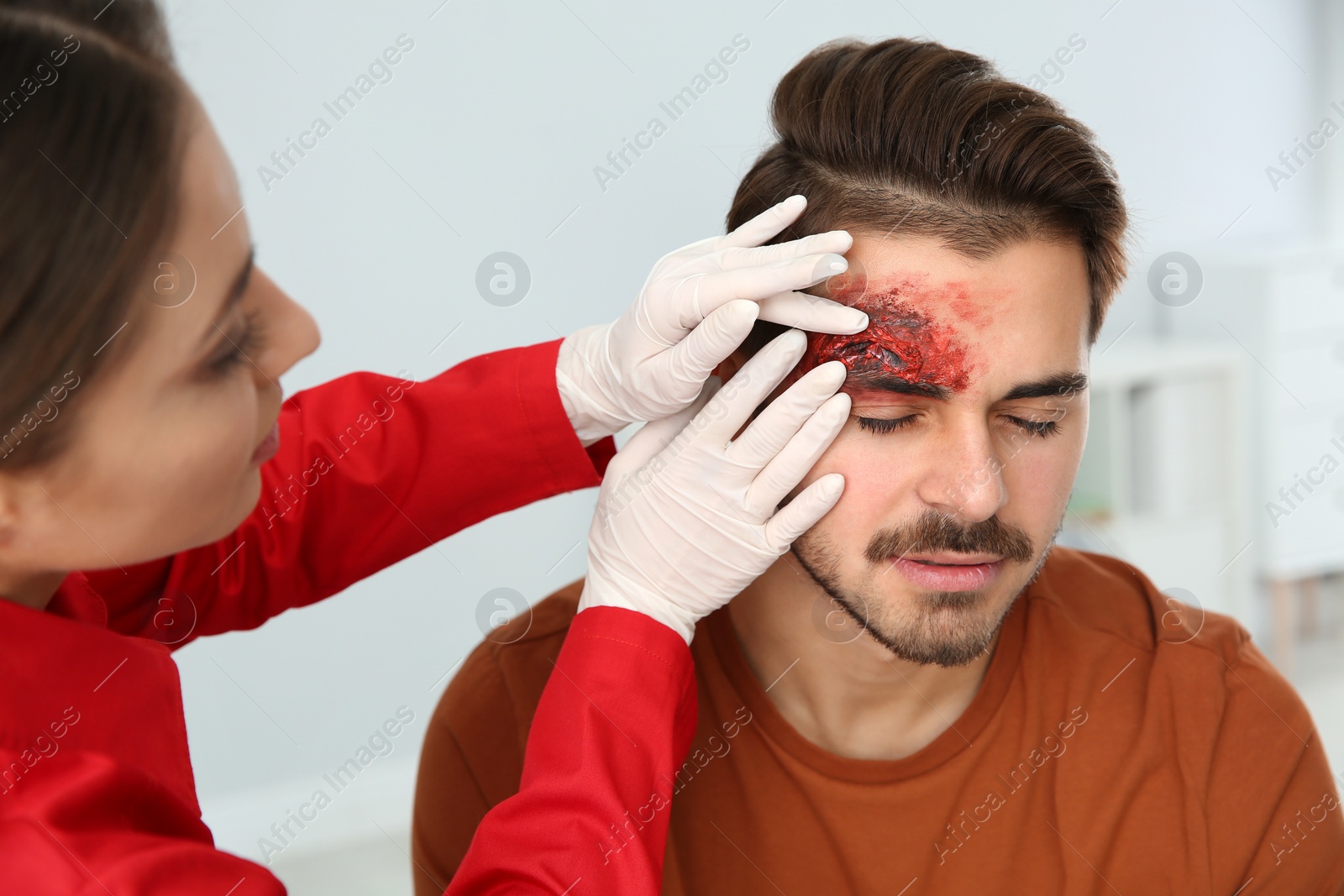 Photo of Nurse examining young man's head injury in clinic. First aid