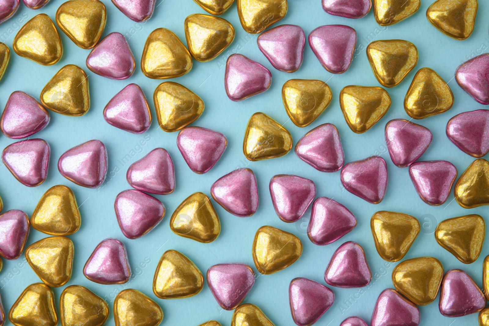 Photo of Many delicious heart shaped candies on light blue background, flat lay