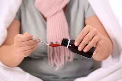 Photo of Ill mature woman taking cough syrup, closeup