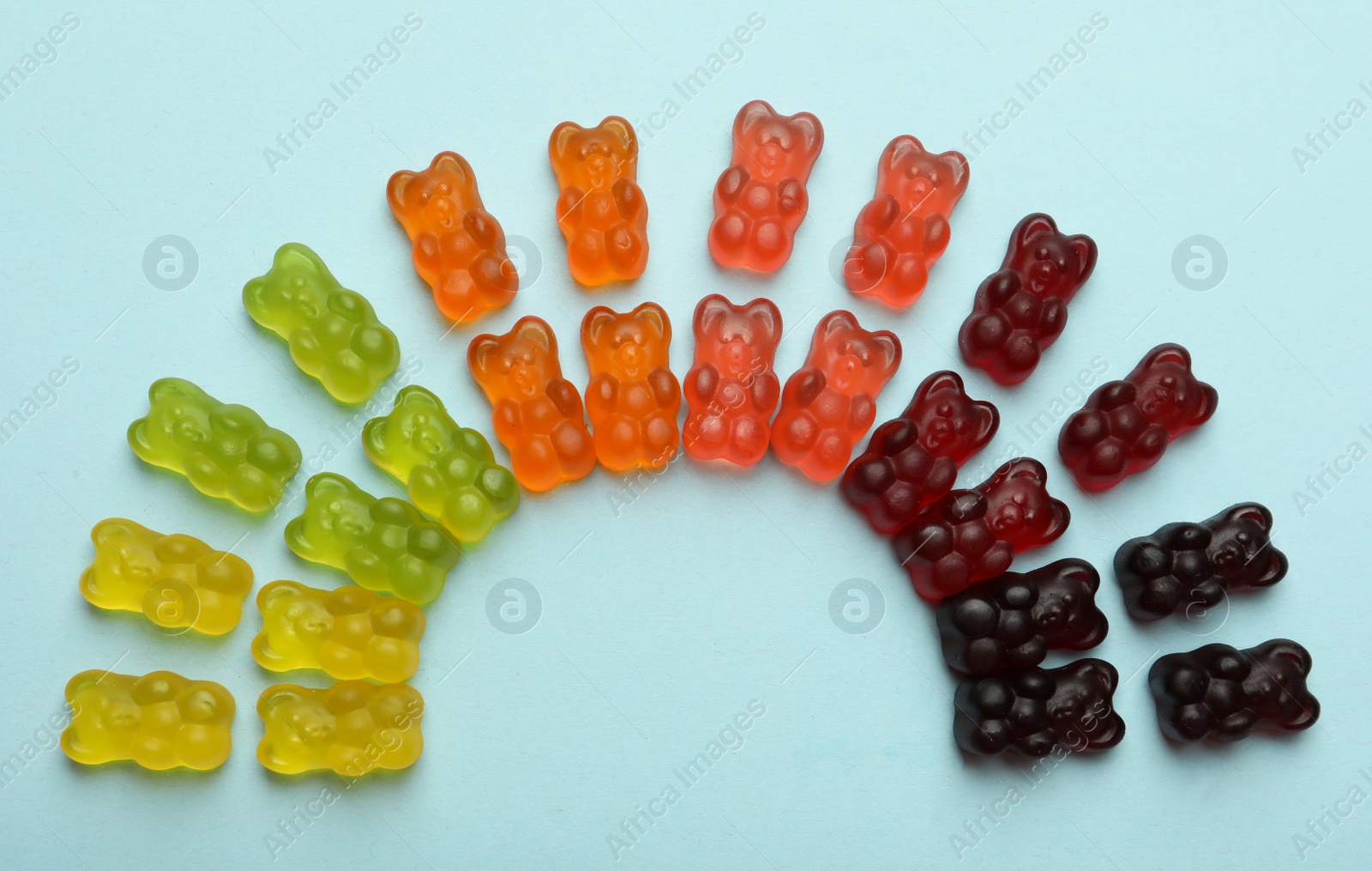 Photo of Delicious gummy bear candies on light blue background, flat lay