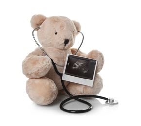 Photo of Ultrasound photo of baby and toy teddy bear on white background. Concept of pregnancy