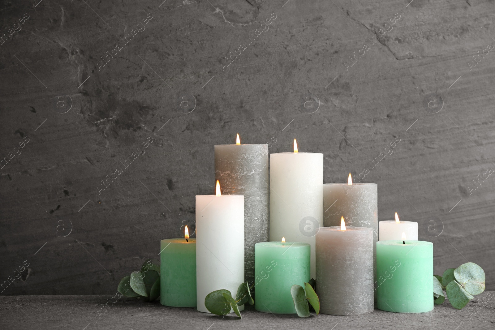 Photo of Composition with burning candles on table against grey background