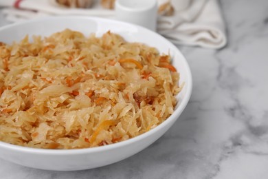 Photo of Bowl with tasty sauerkraut on white marble table, closeup. Space for text