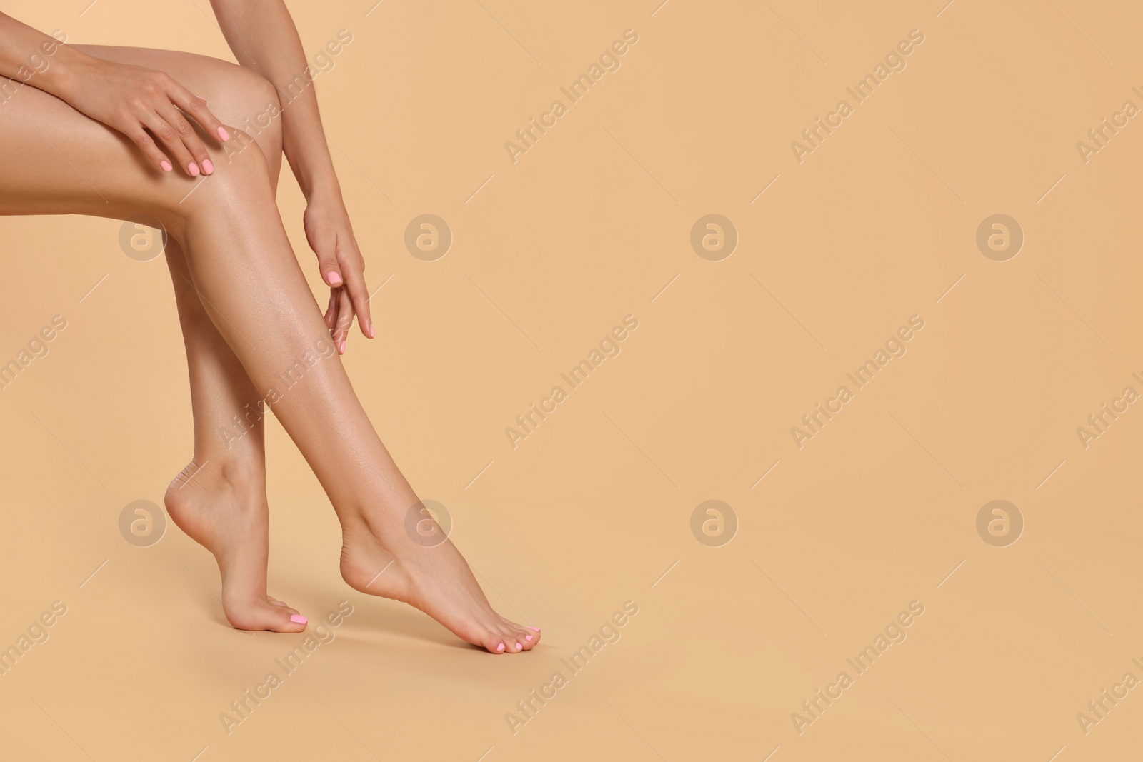 Photo of Woman with beautiful long legs on beige background, closeup. Space for text