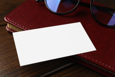 Photo of Blank business card, notebook and glasses on wooden table, closeup. Mockup for design