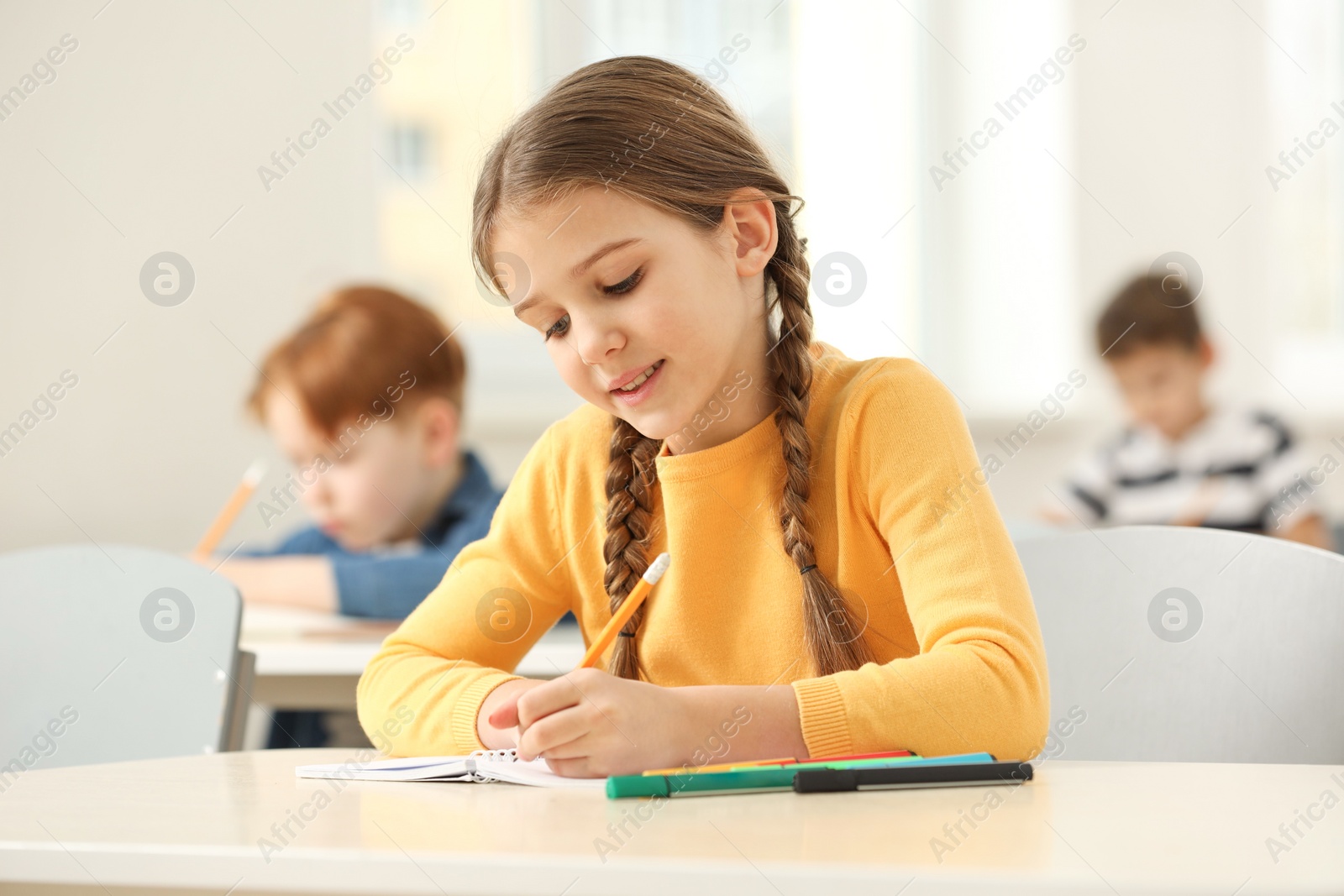 Photo of Smiling little girl studying in classroom at school