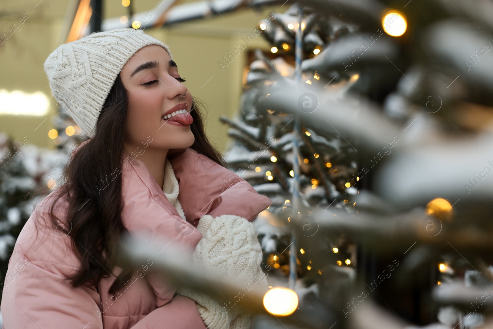 Photo of Portrait of funny woman showing tongue on city street in winter