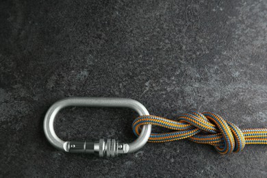 One metal carabiner with rope on black table, top view. Space for text