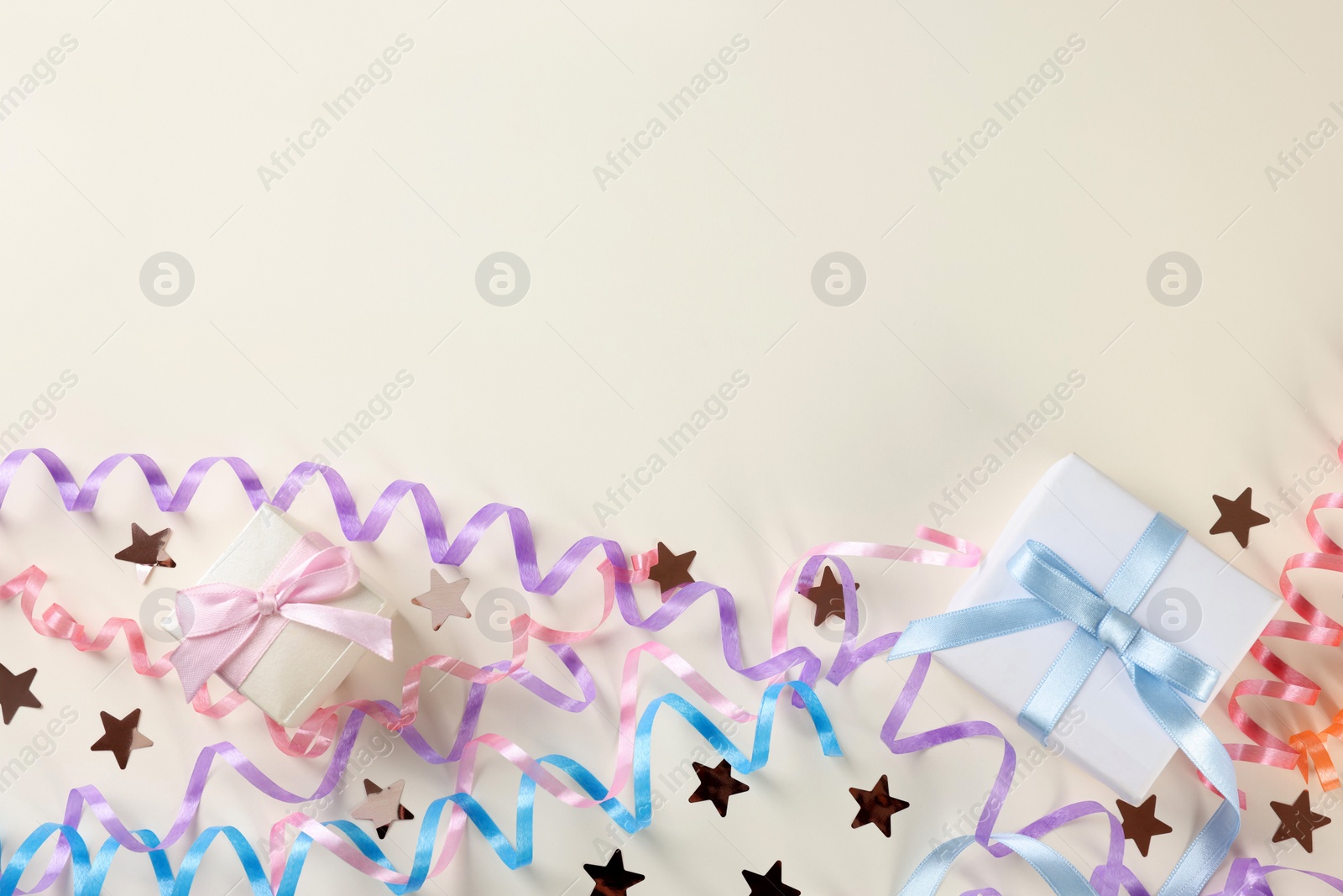 Photo of Colorful serpentine streamers, gift boxes and confetti on white background, flat lay. Space for text