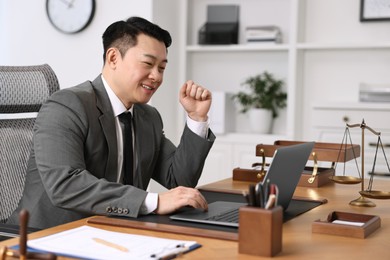 Notary working with laptop at wooden table in office