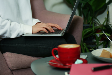 Photo of Blogger working with laptop in armchair indoors, closeup