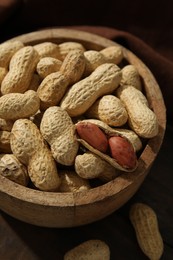 Photo of Fresh unpeeled peanuts in bowl on wooden table, closeup