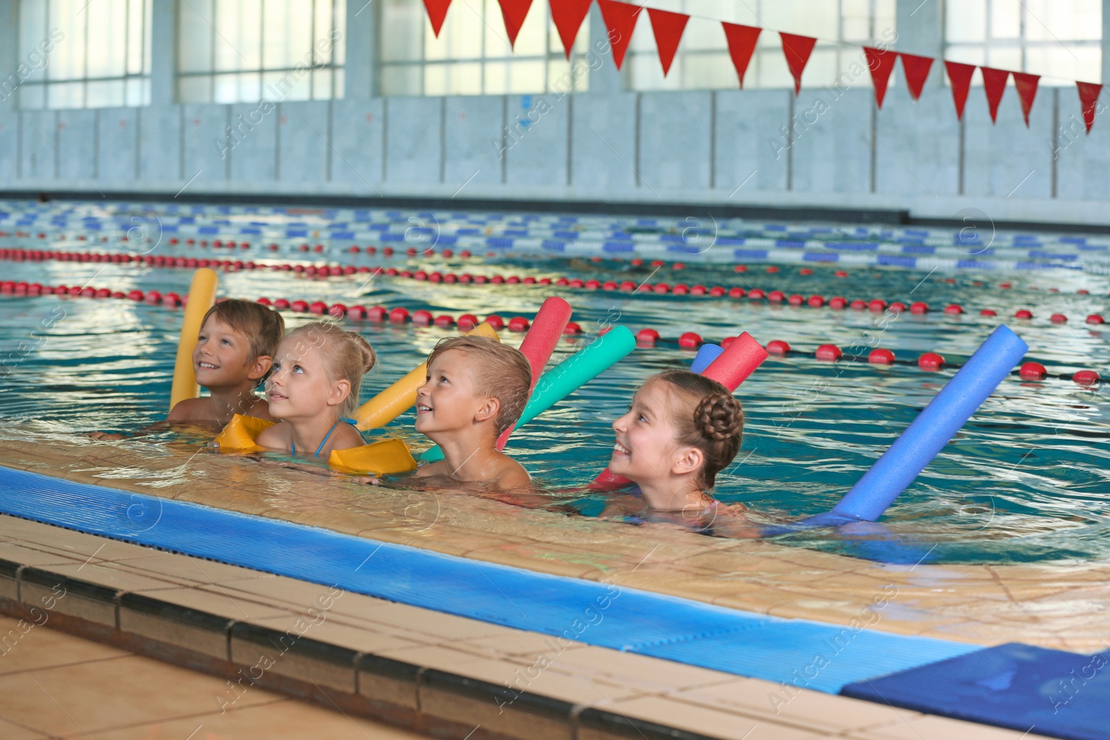 Photo of Little kids with swimming noodles in indoor pool