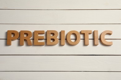 Photo of Word Prebiotic made of wooden letters on white table, flat lay