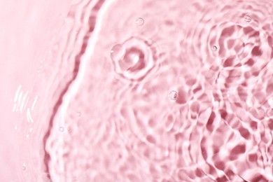 Photo of Closeup view of water with rippled surface on pink background