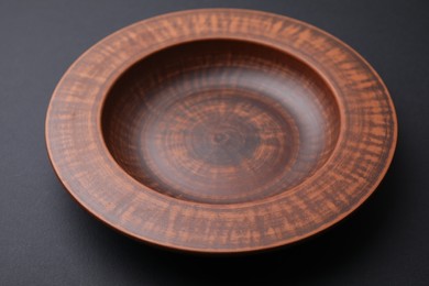 Photo of One ceramic bowl on black background, closeup