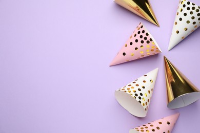 Bright party hats on lilac background, flat lay. Space for text