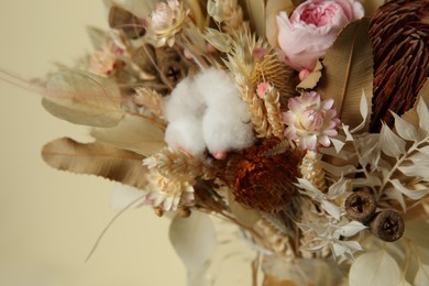 Beautiful elegant dried flower bouquet near beige wall, closeup view