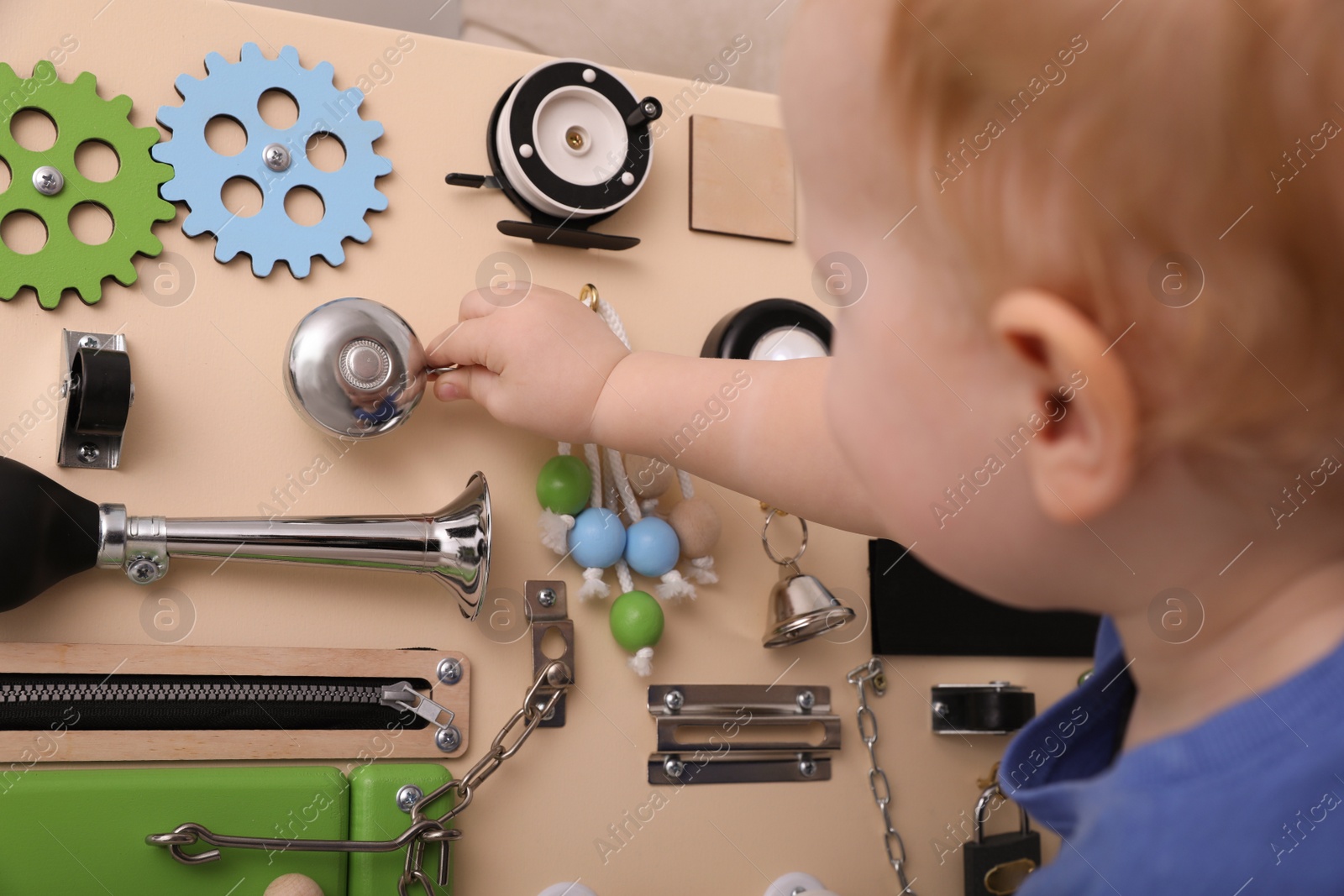 Photo of Cute little boy playing with busy board, focus on hand