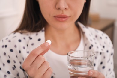 Photo of Young woman taking abortion pill indoors, closeup