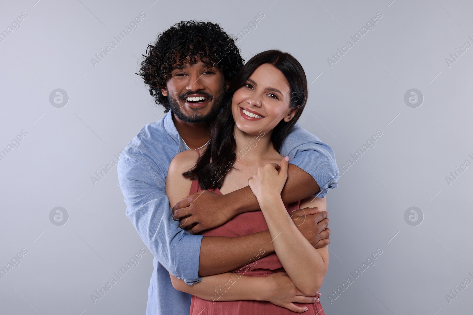 Photo of International dating. Happy couple hugging on light grey background