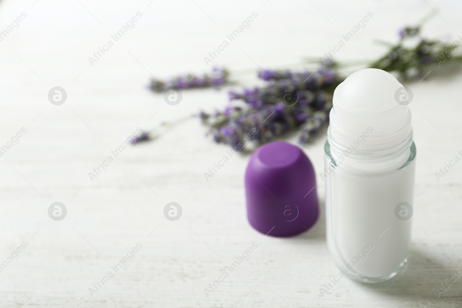 Photo of Female deodorant and lavender flowers on white wooden table. Space for text