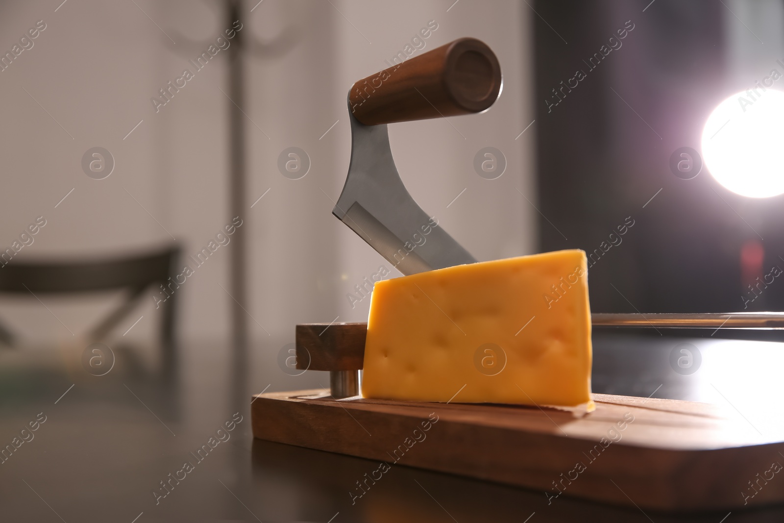 Photo of Slicer and piece of cheese on table, closeup