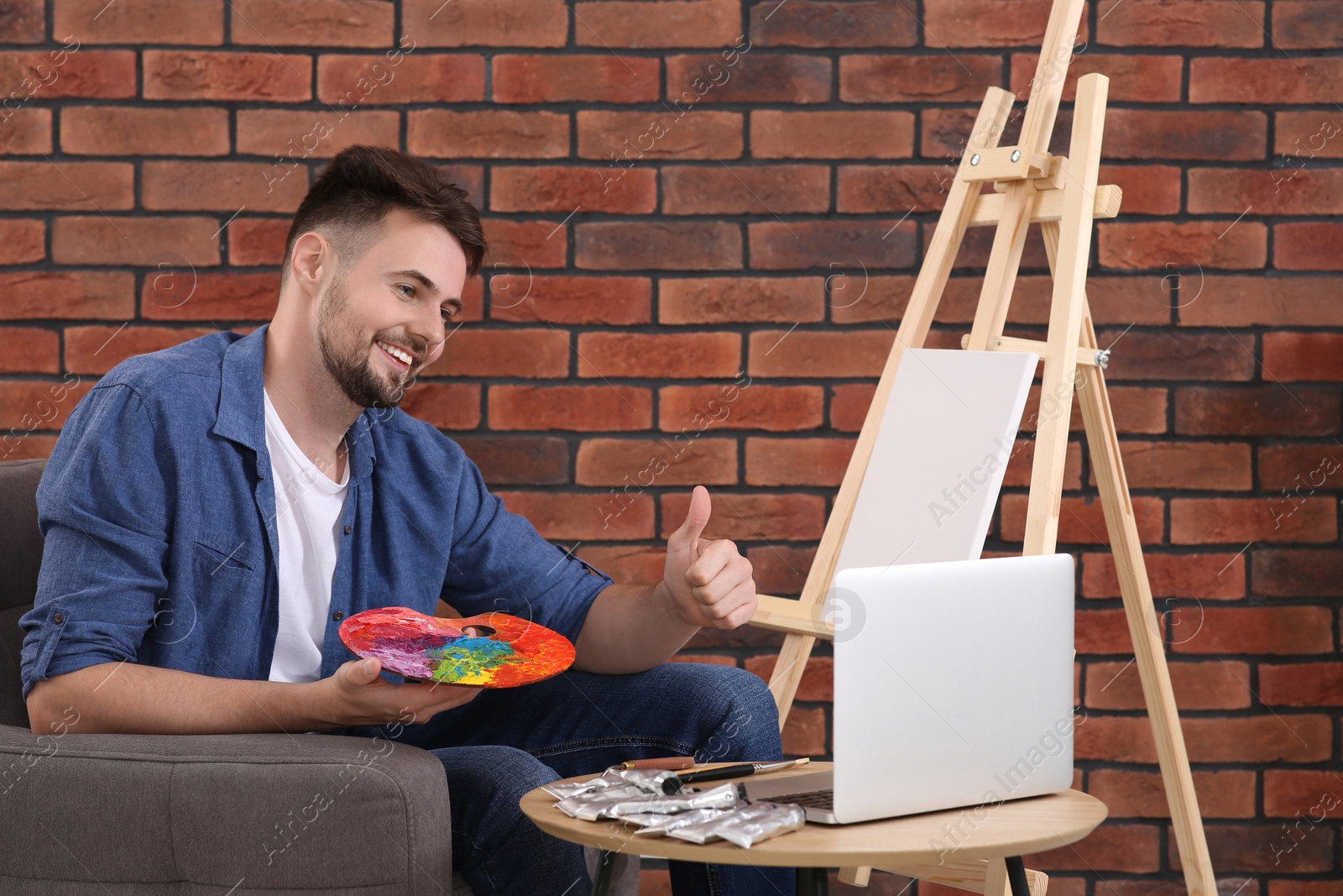 Photo of Happy man learning to draw with online course on laptop at home. Time for hobby