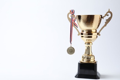 Photo of Shiny golden trophy cup and medal on white background