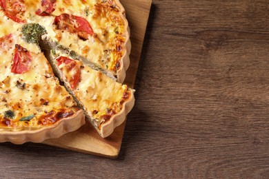 Photo of Tasty quiche with tomatoes and cheese on wooden table, above view. Space for text