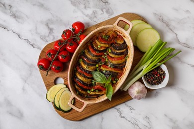 Photo of Delicious ratatouille and ingredients on white marble table, top view