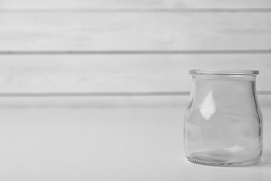 Photo of Empty glass jar on white table, space for text