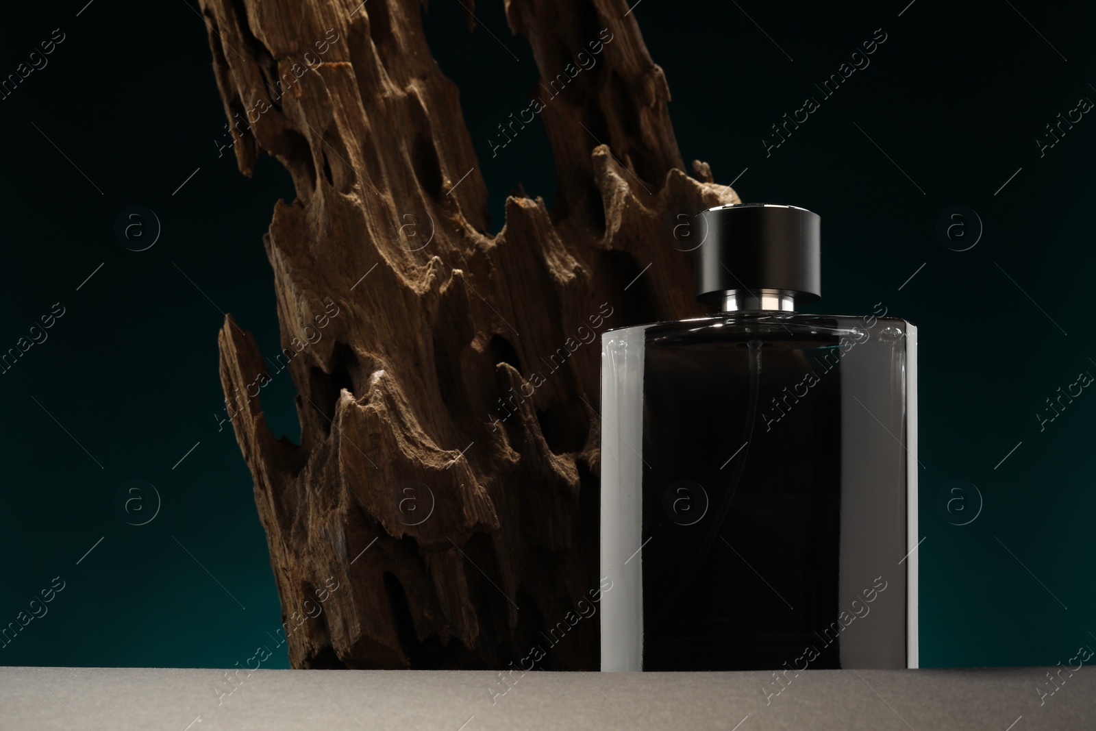 Photo of Luxury men`s perfume in bottle on grey table against color background, space for text