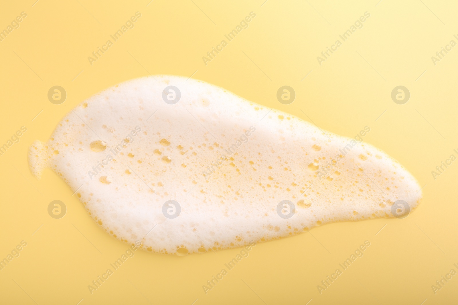 Photo of Sample of fluffy foam on yellow background, top view