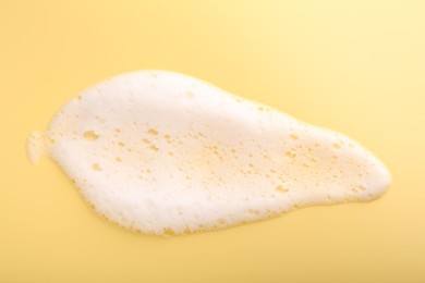 Photo of Sample of fluffy foam on yellow background, top view